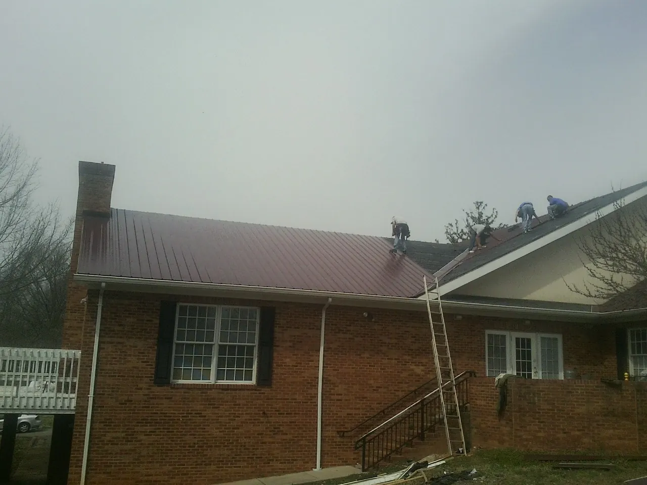 Crew setting red metal roofing panels on a brick home in Buffalo Mills