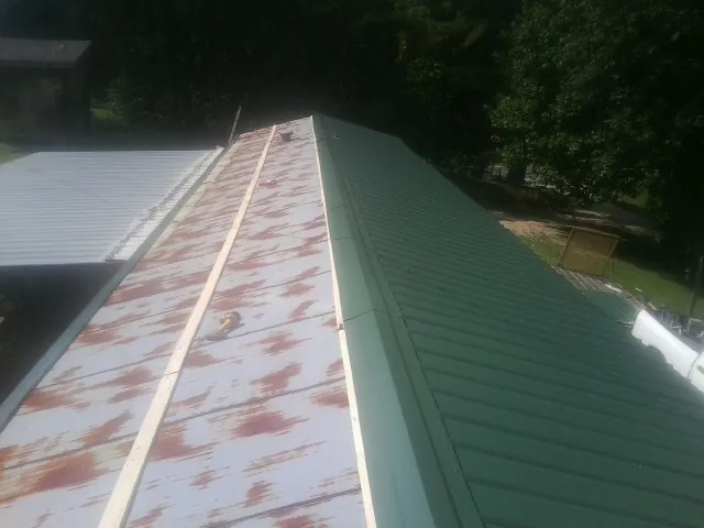 Old rusted panels beside newly installed green metal roofing — Wind Damage Roof Repair by Roofing Brothers in Buffalo Mills