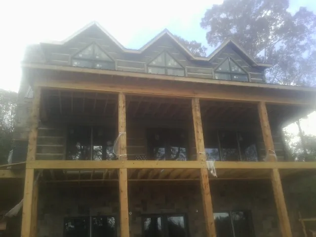 Dormers and porch framing on a large log home under construction — Roof Coating work by our crew in Buffalo Mills