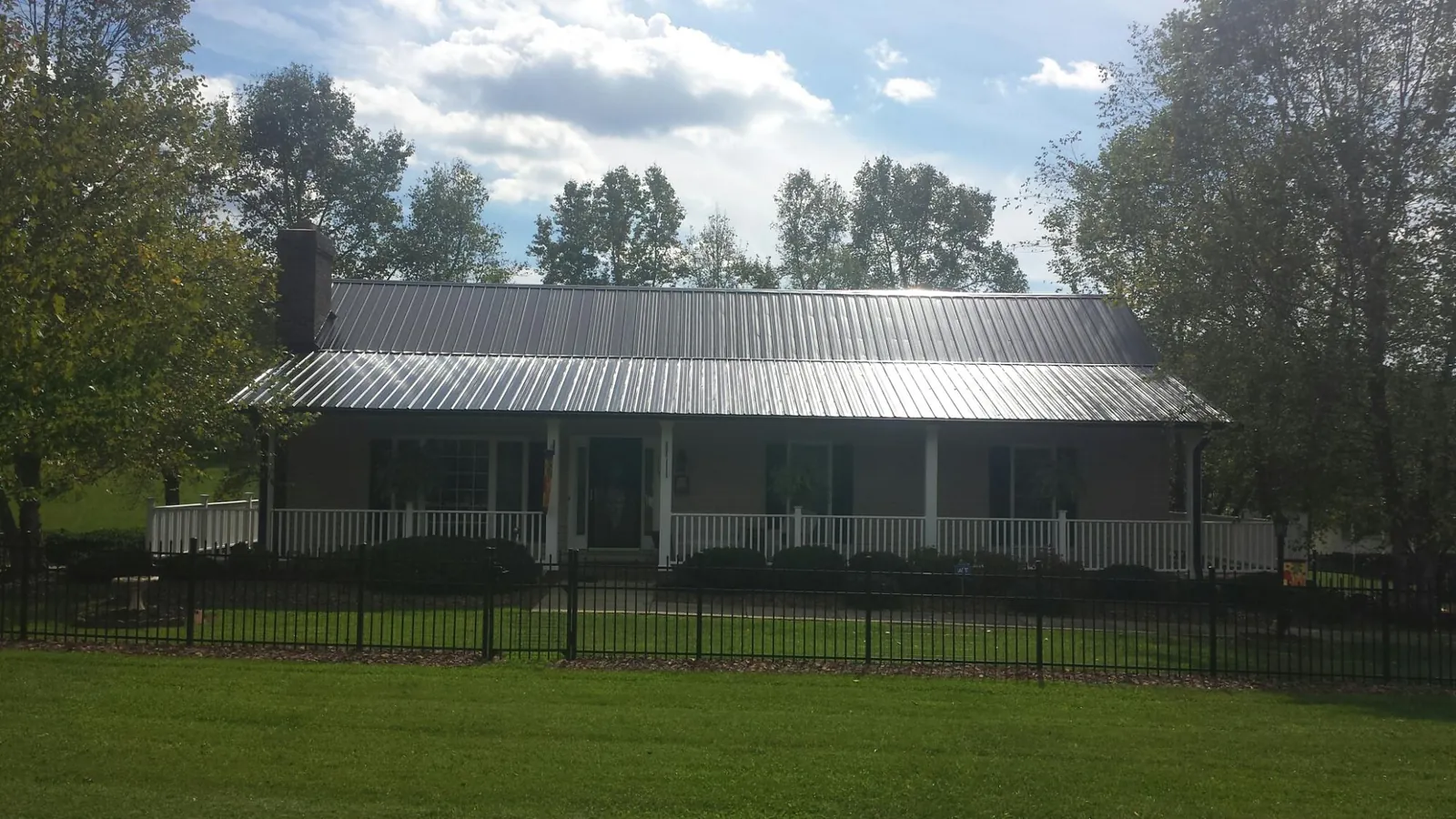 Gray metal roof on a brick ranch with a full width front porch — Gutter Guard Installation work by our crew in Buffalo Mills