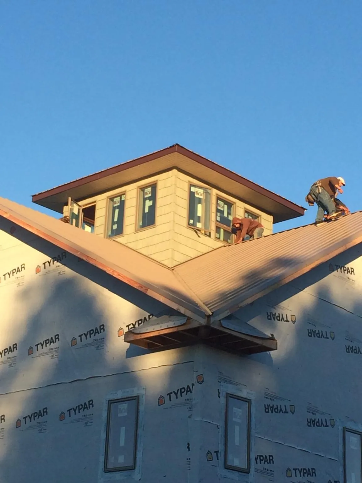 Roofers working around a rooftop cupola on a new metal roof at sunset — Roof Waterproofing in Buffalo Mills by Roofing Brothers